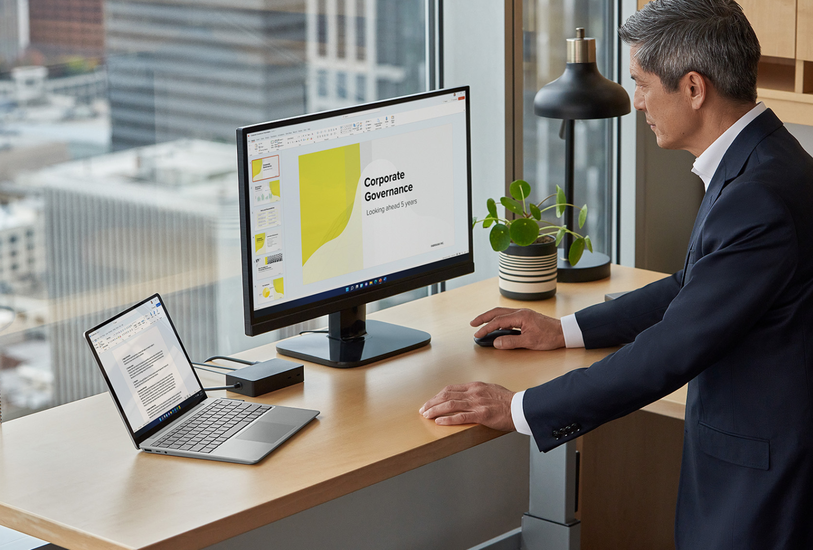 A man stands in front of his home office while interacting with a Surface Laptop Go 3