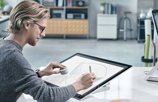 Surface Studio 2 のディスプレイで Surface Dial を使用している男性
