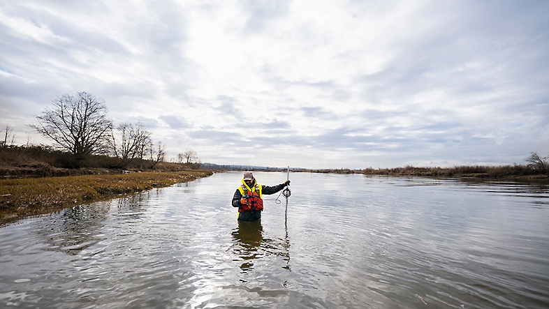 A person standing waist deep in a river. 