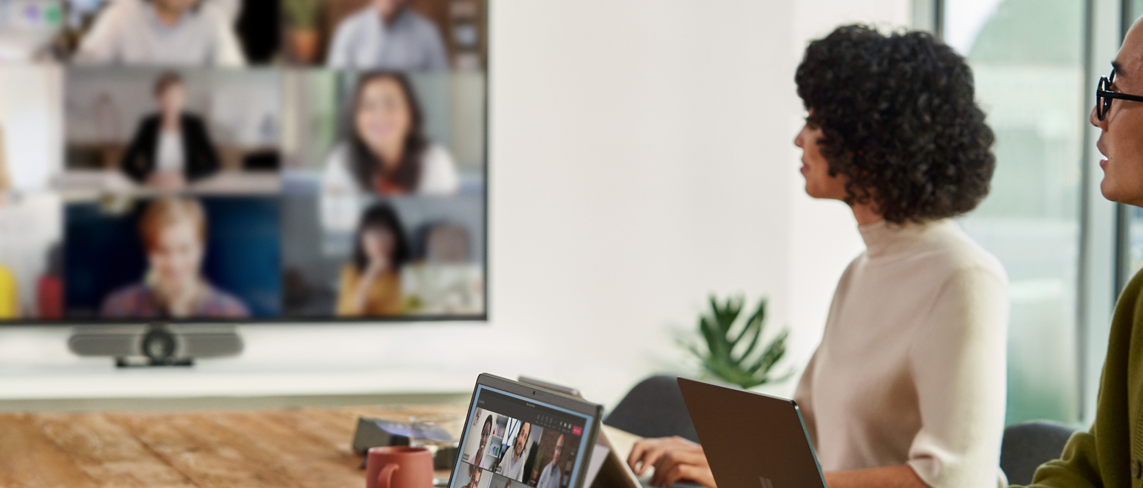 A group of people sitting at a table watching a video conference.