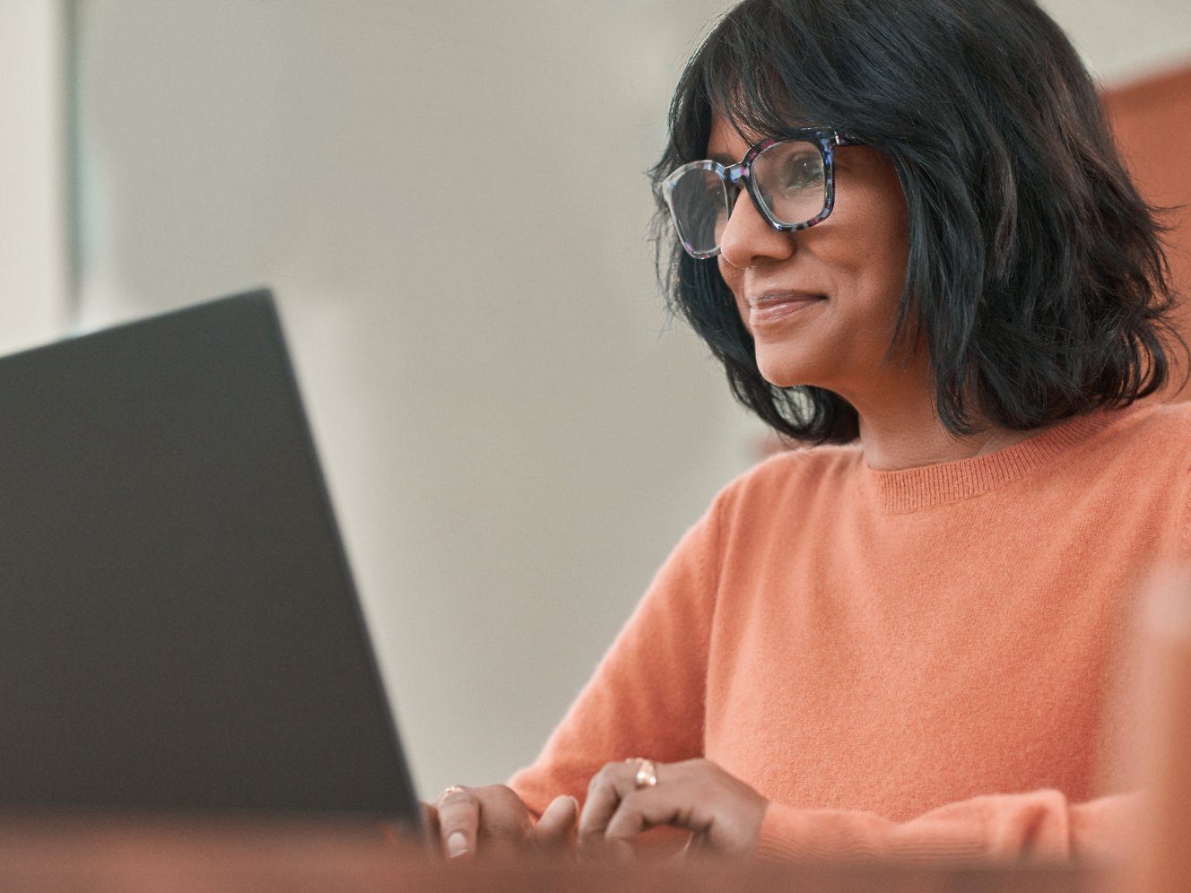 En kvinde med briller, der arbejder med en bærbar computer