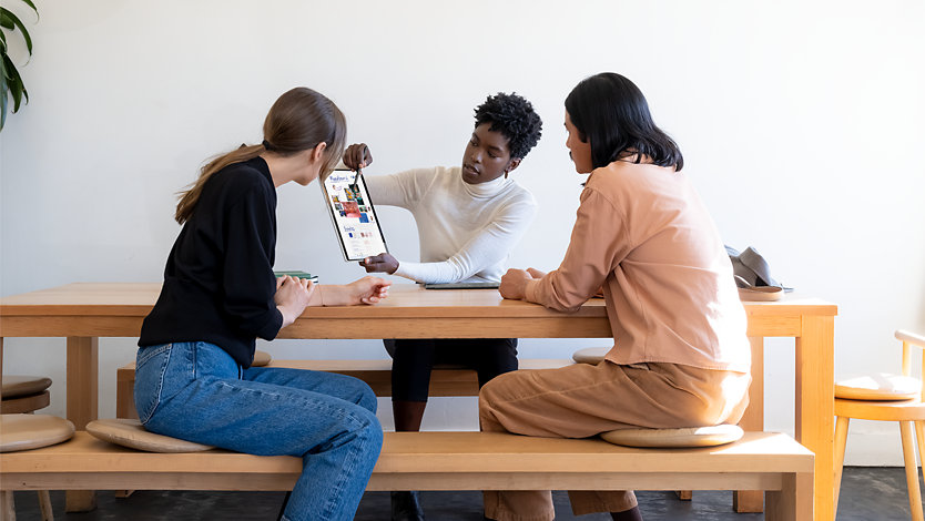 A person presenting a design to others at a table with a Slim Pen and a Surface Laptop Studio in tablet mode.