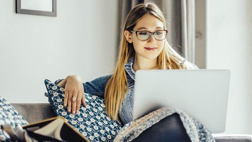 A person uses a laptop on a couch.