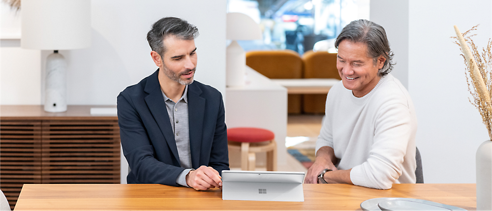 Two person sitting at a table watching tablet