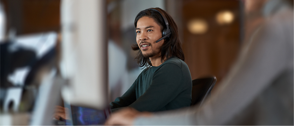 A person wearing a headset and looking at a computer