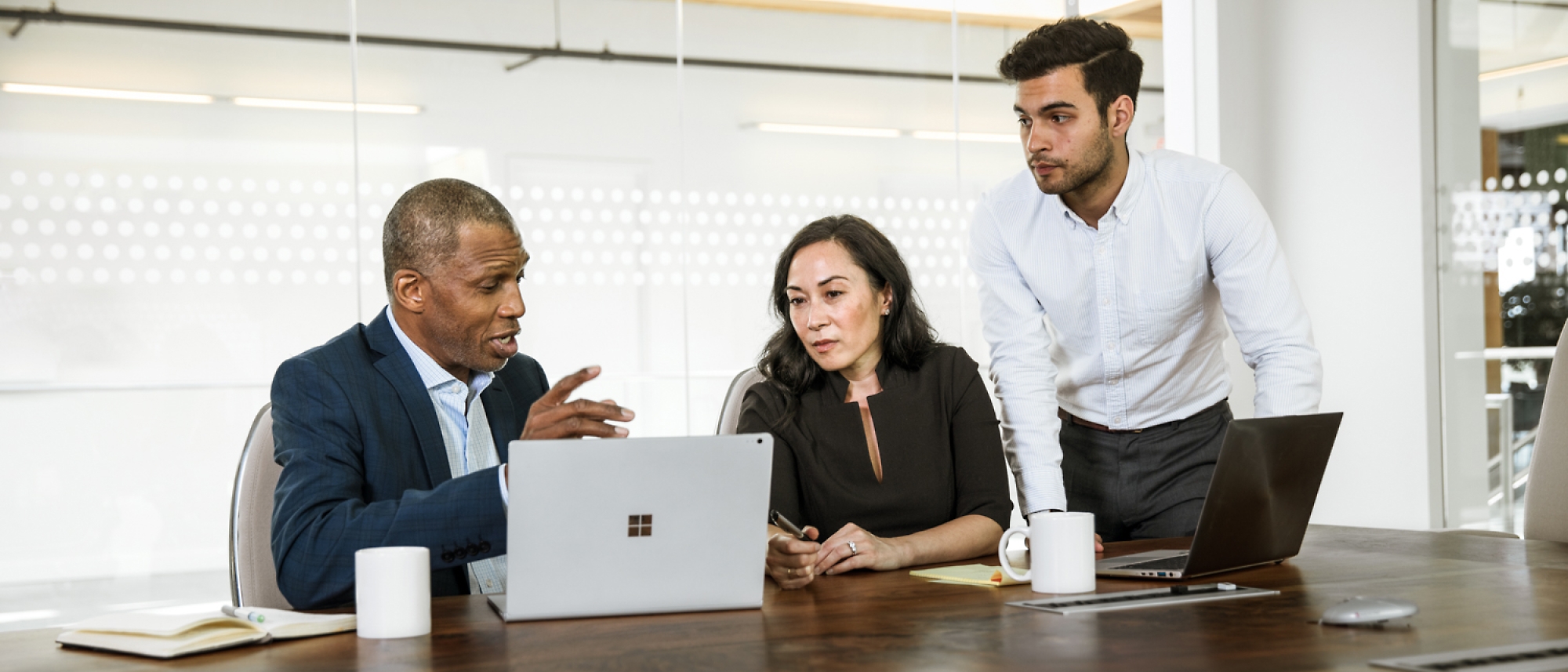 3 personas dialogando en una sala de oficina con un portátil