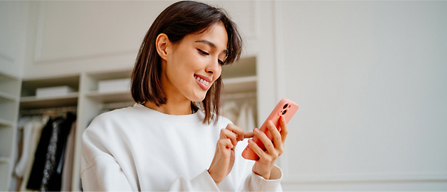 Une personne utilise un téléphone portable et sourit.