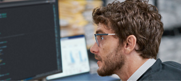 A man is wearing glasses and watching a desktop screen.