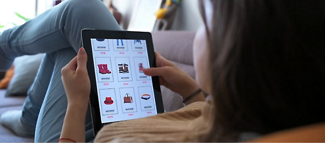 A girl lying on bed and watching a shoping website on tablet.