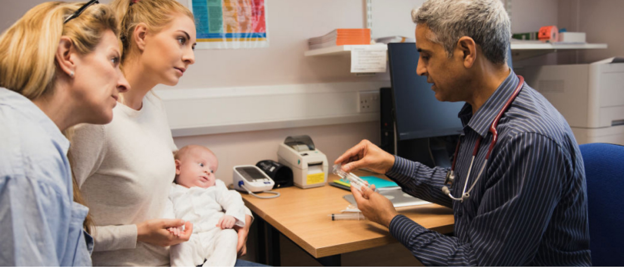 A doctor is attending to a baby patient who is accompanied by her mother