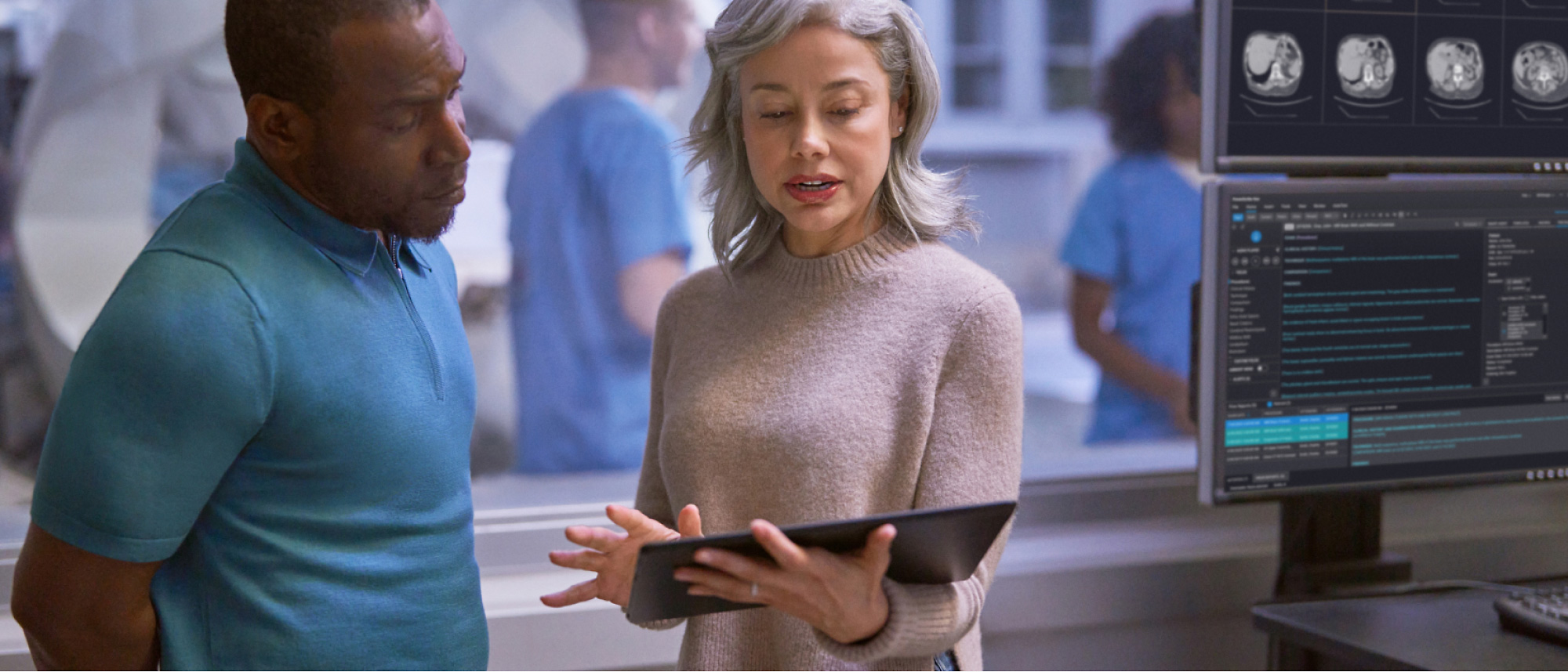 A person holding a tablet and talking with another person