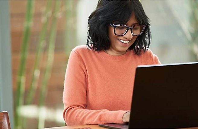 Eine Frau, die eine Brille trägt und einen Laptop verwendet.