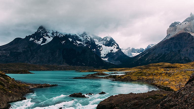 A flowing body of water surrounded by snow-capped mountains