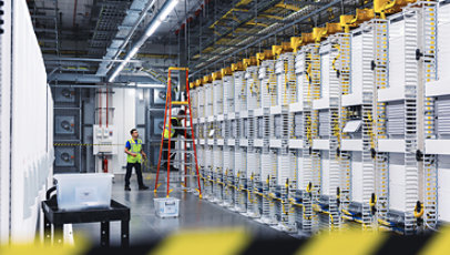 Datacenter employees installing new server rack cables near a ladder with caution tape.