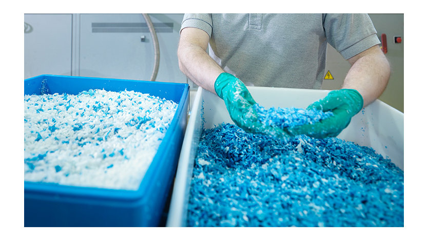 Worker inspecting recycled plastics in plastics factory.