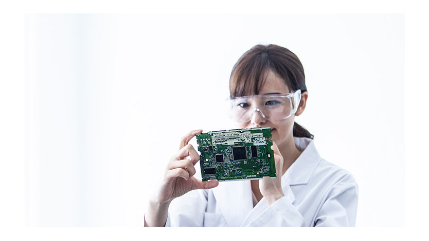 Female researcher inspects an electronic board.