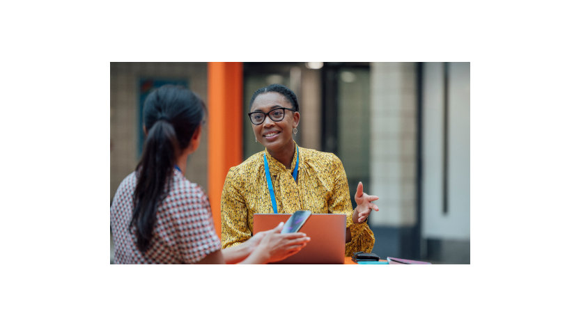 Two female teachers sitting at a table, having a discussion.