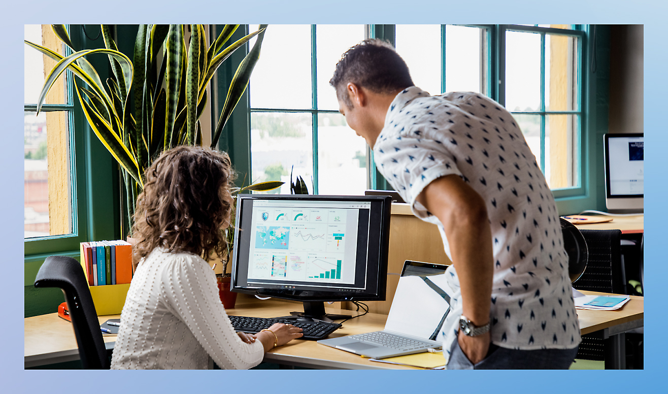 Woman showing man her monitor with graph on it 