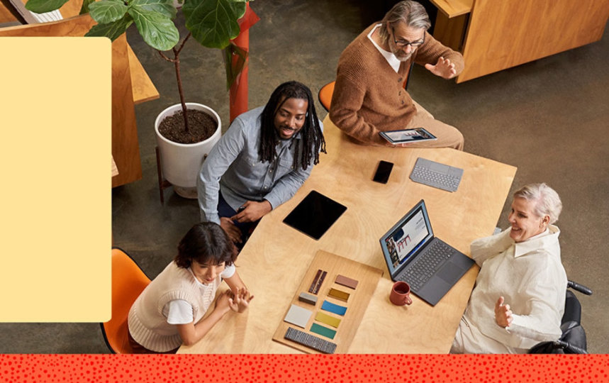 People gathered around a table with tablets and laptops 