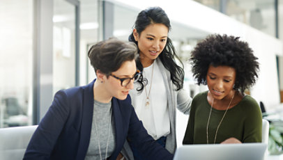 A group of three women looking at a laptop and having a discussion.