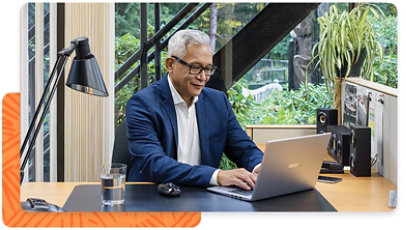 A person sitting at their desk in an office environment, typing on a laptop