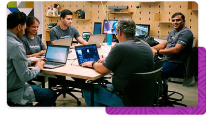 A group of Microsoft employees wearing Hackathon apparel, together working on laptops