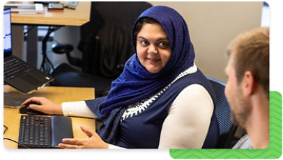 A person sitting behind a computer, talking to someone out of view