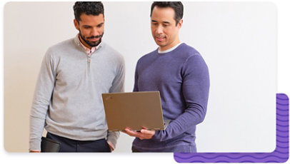 Two people standing together, looking at a laptop