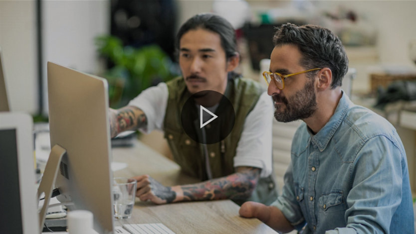 Two people working together at a computer monitor