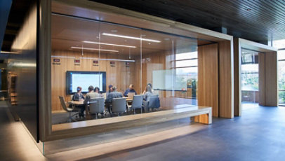 Outside of a conference room or board room meeting including people sitting around table in a room with international time clocks.