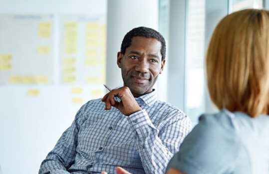 Two colleagues talking together while sitting in a modern office.