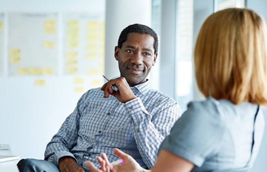 Two colleagues talking together while sitting in a modern office.