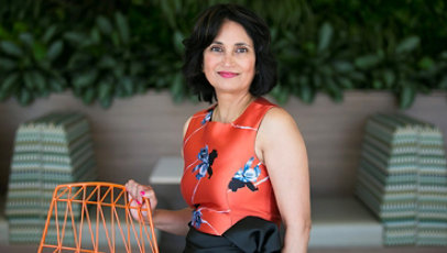 Microsoft Board Member Padmasree Warrior standing next to a chair, smiling.