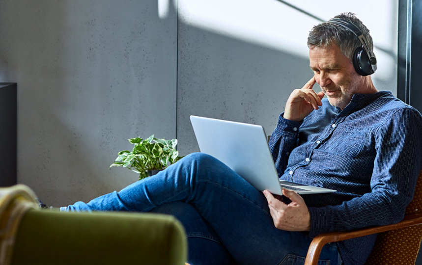 Man wearing headphones listening to music on a laptop.