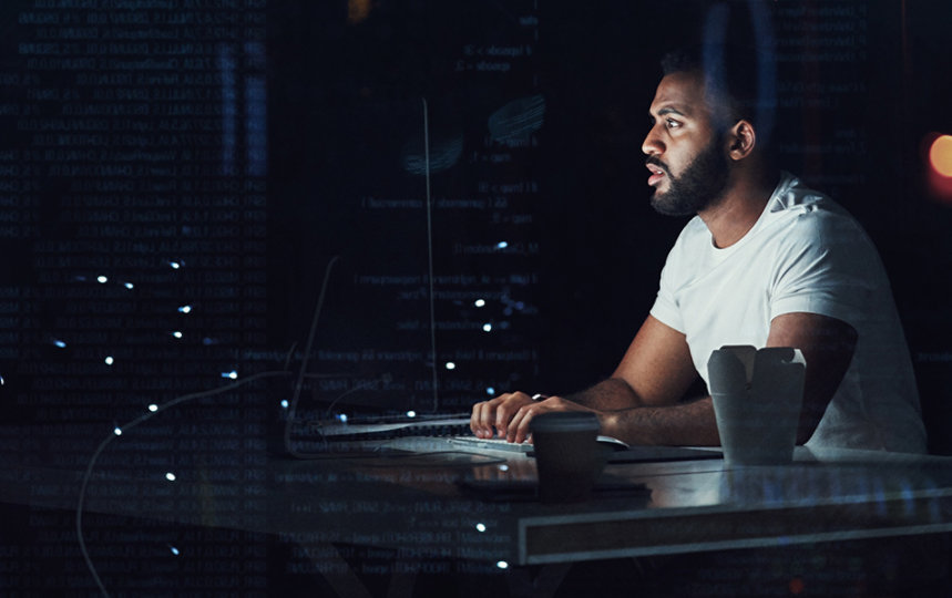 Programmer working on a computer in an office at night.