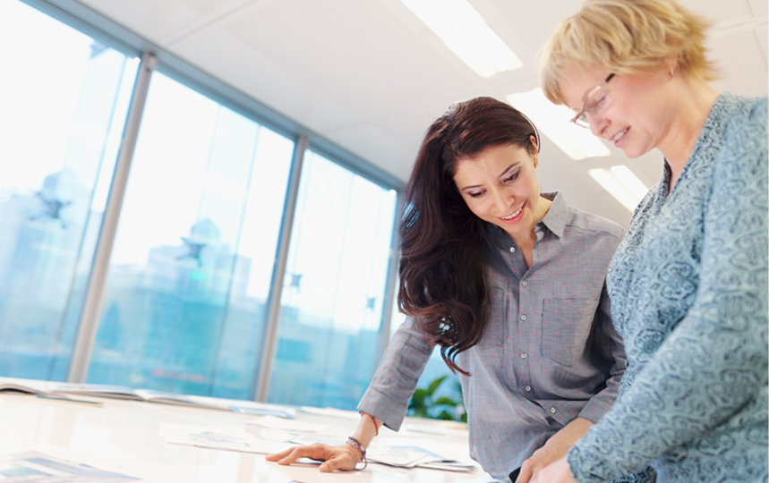 Two women working at a stand-up desk. 