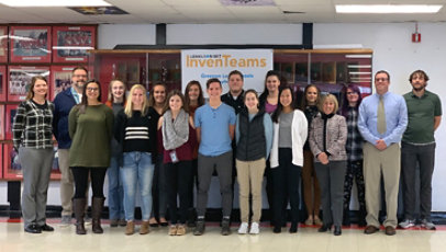 A group of students and teachers standing in front of lockers in a school hallway