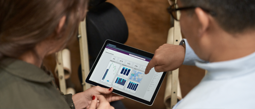 Two professionals analyzing data on a tablet screen, focusing intently on graphs displayed.