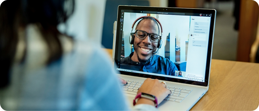 Person using a laptop to conduct a video call with a smiling individual on the screen.