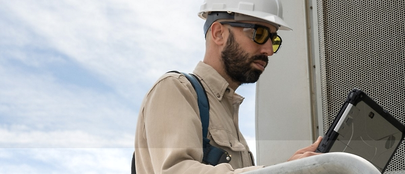 A man in a hard hat is using a laptop