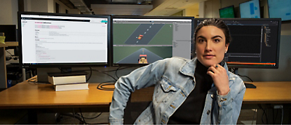 A woman leaning in front of two monitors