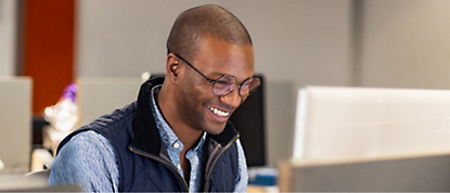 A man is smiling while working on a computer