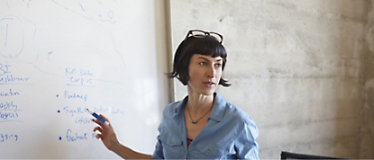 A woman is standing in front of a whiteboard