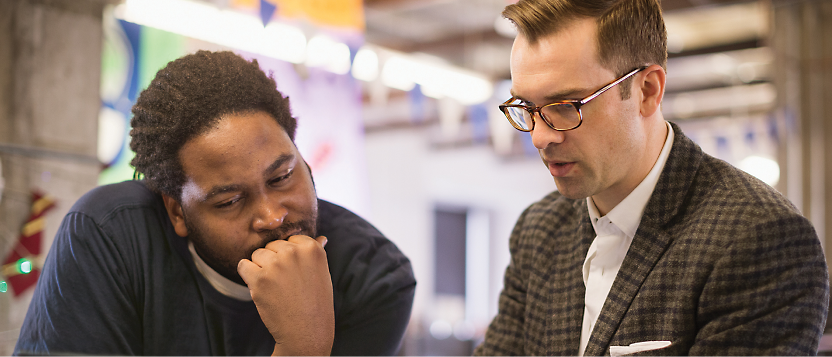 Two men in a discussion, one appears pensive while listening to the other.