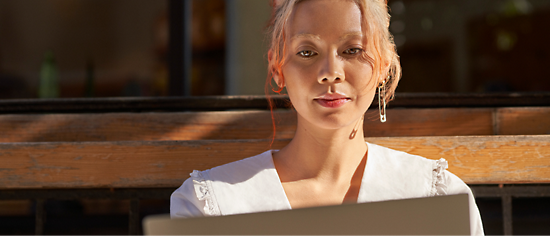 A woman sitting on a bench with a laptop.