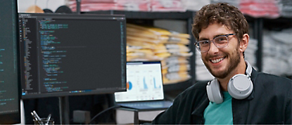 An image of a man with headphones in front of a computer screen