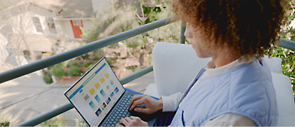 A woman using a laptop on a balcony.