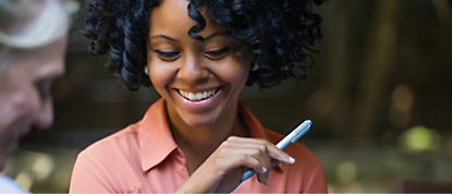 A woman smiles while holding a pen