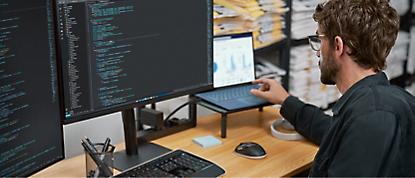 A man is sitting at a desk with two monitors in front of him