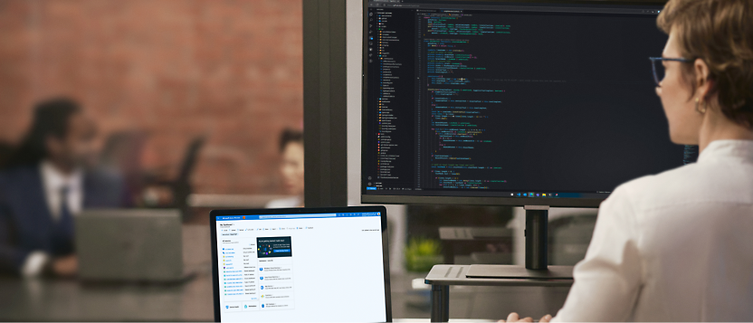 A person working on a computer with code on the screen in an office environment.